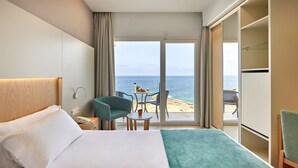 A hotel room with a bed, a small table with chairs, a view of the sea, and a wardrobe. - Universal Hotel Cabo Blanco - Adults Only (Ses Salines)