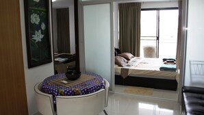 Ein Hotelzimmer mit Bett, einem kleinen Tisch mit einer Schüssel, einem Stuhl, einem Fenster mit Vorhängen und einem Bild an der Wand.