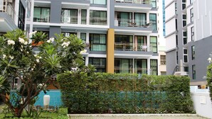 Ein mehrstöckiges Wohngebäude mit Balkonen, einem Garten mit blühenden Pflanzen und einer Wand mit blauen Fliesen.