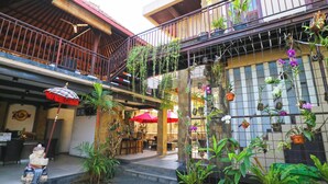 A courtyard with a dining area, outdoor seating, and potted plants. - The Swaha Ubud Hotel (Batubulan)