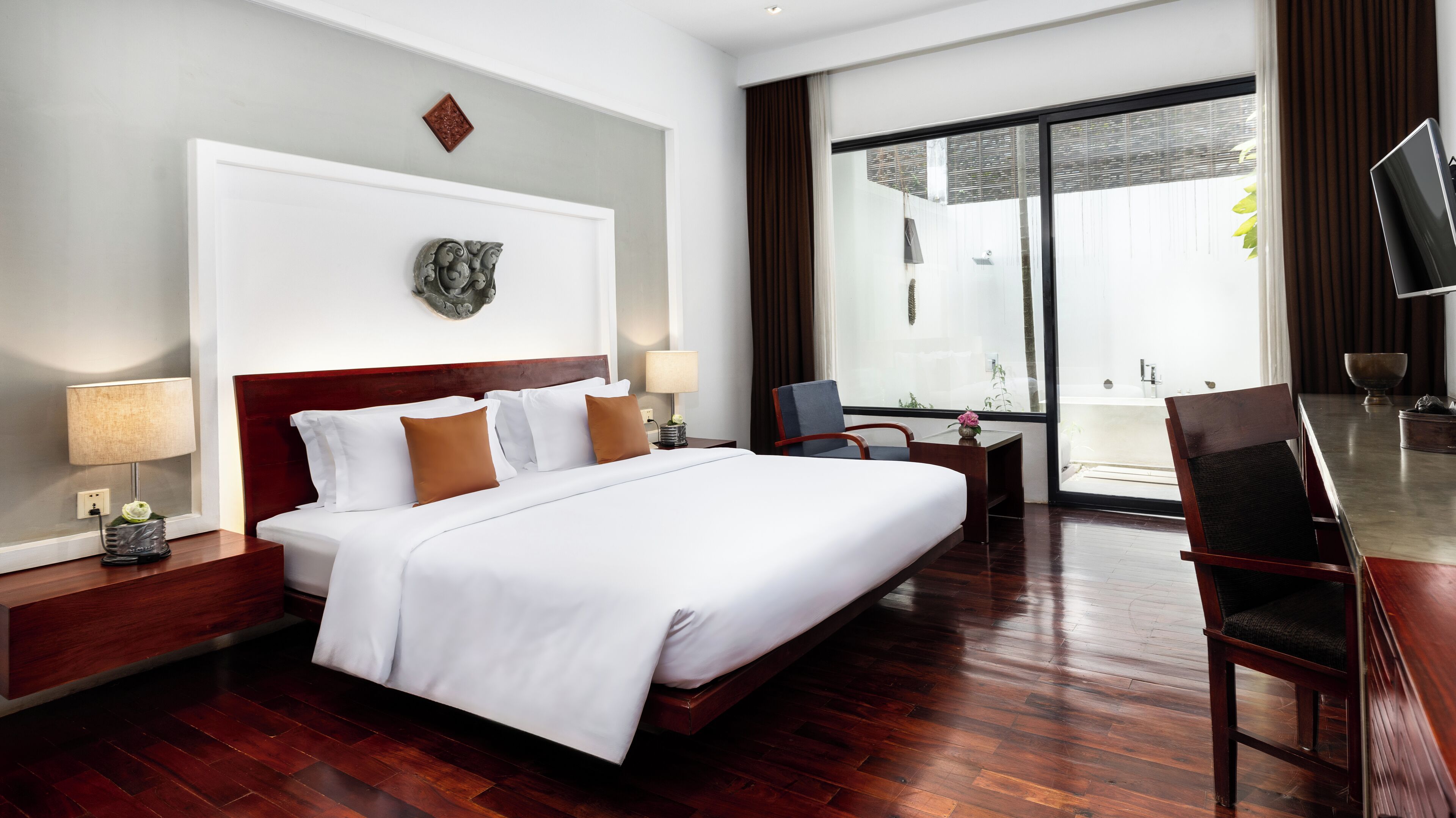 A hotel room with a large bed, a desk, a chair, and a view of the outside.