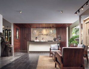 Een receptiegedeelte met een houten receptiebalie, ingelijste foto’s en een stenen muur waarop de naam 'LYNN' staat.