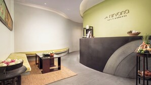 Ein Empfangsbereich mit einer gewölbten Wand, einer Rezeption und einer Sitzecke mit einer Bank und Tischen.