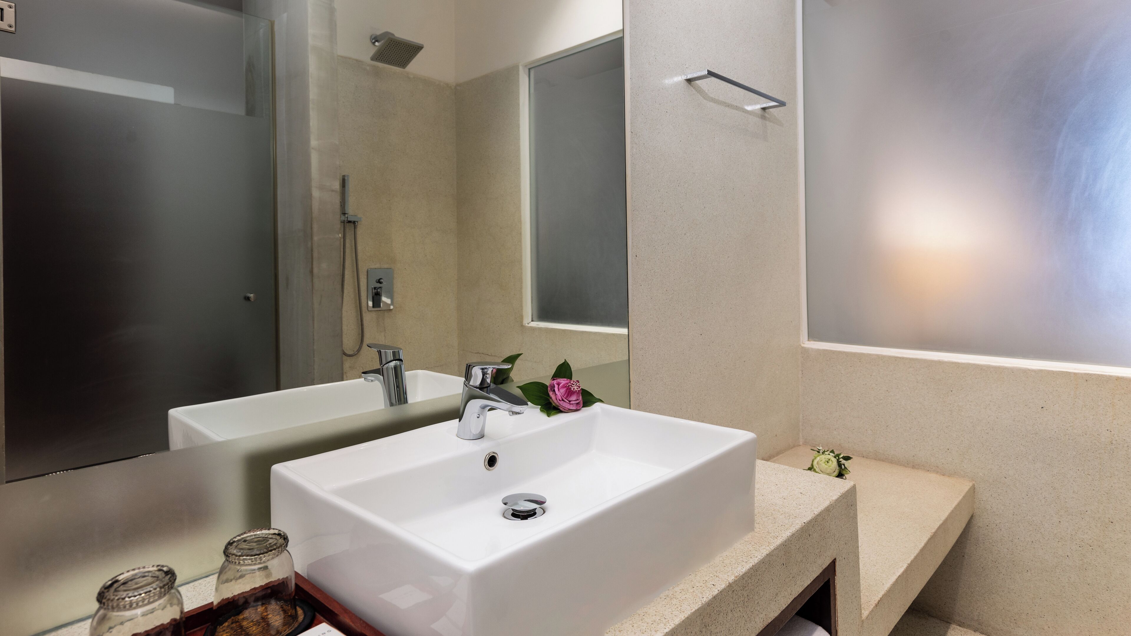 Un baño moderno con un lavamanos blanco grande, un espejo y una zona de ducha.