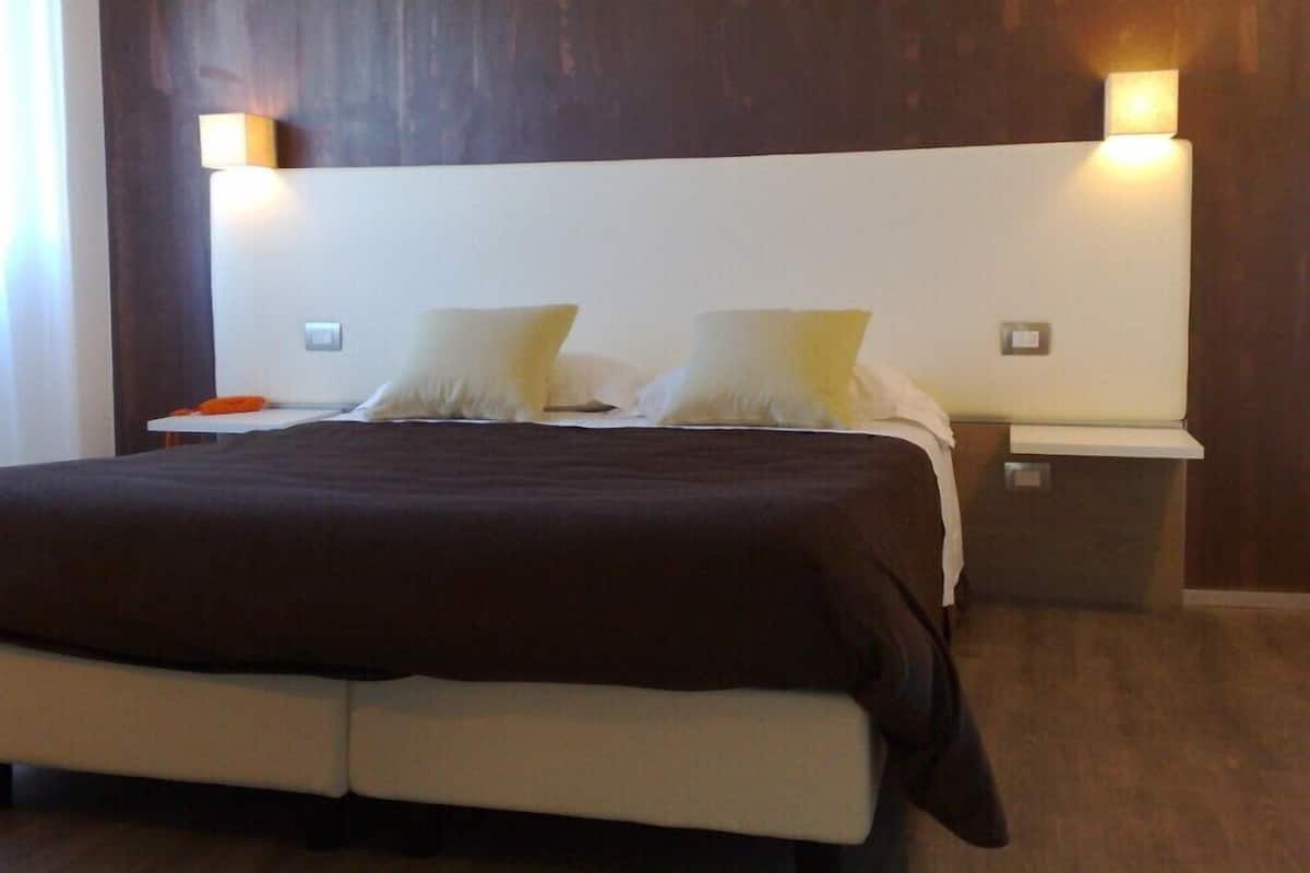 Een hotelkamer met een groot bed, twee nachtkastjes en wandlampen.