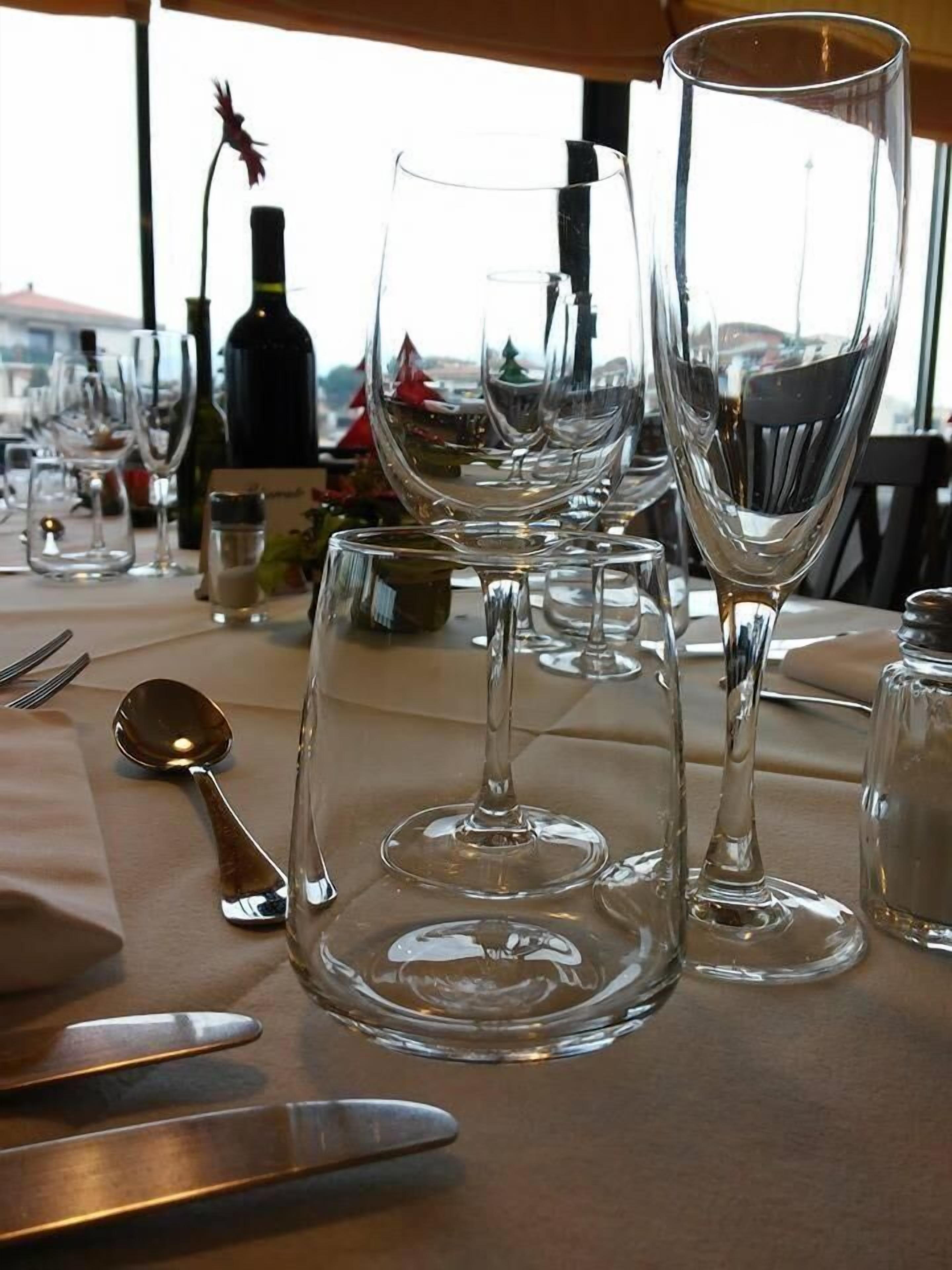 A dining table set with wine glasses, a bottle, and cutlery.