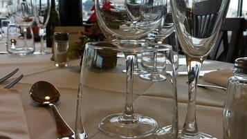 A dining table set with wine glasses, a bottle, and cutlery.
