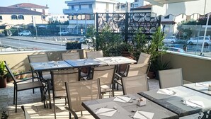 Une terrasse extérieure avec des tables et des chaises, des plantes en pot et une vue sur le paysage urbain.