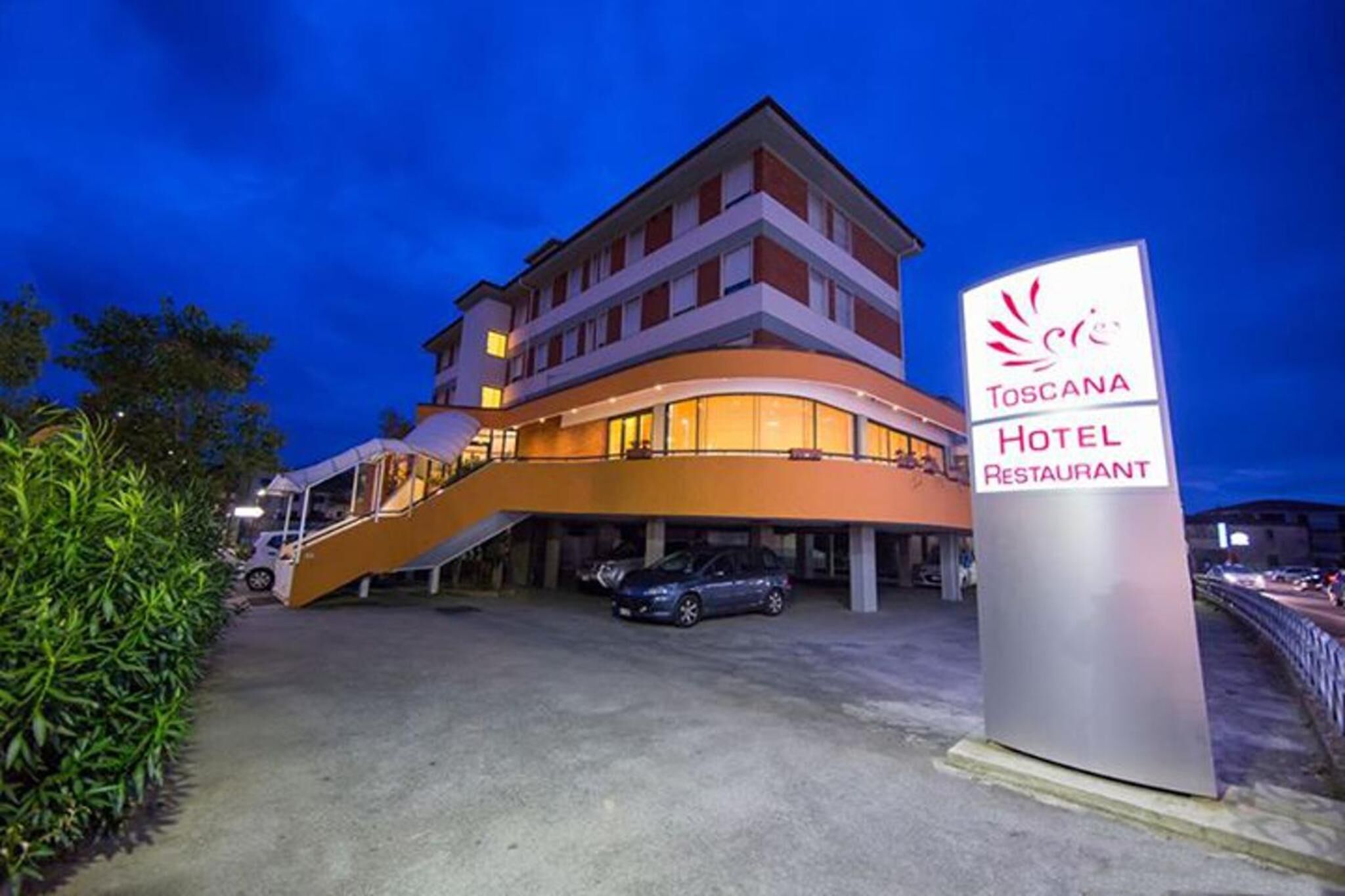 Ein Hotel mit modernem Design, das eine geschwungene Fassade und eine markante Treppe zum Eingang zeigt.