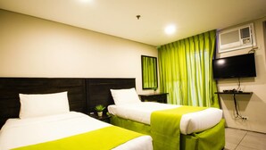 A hotel room with two beds, a flat-screen TV, an air conditioning unit, and a green curtain. - Jade Hotel & Suites (Makati)