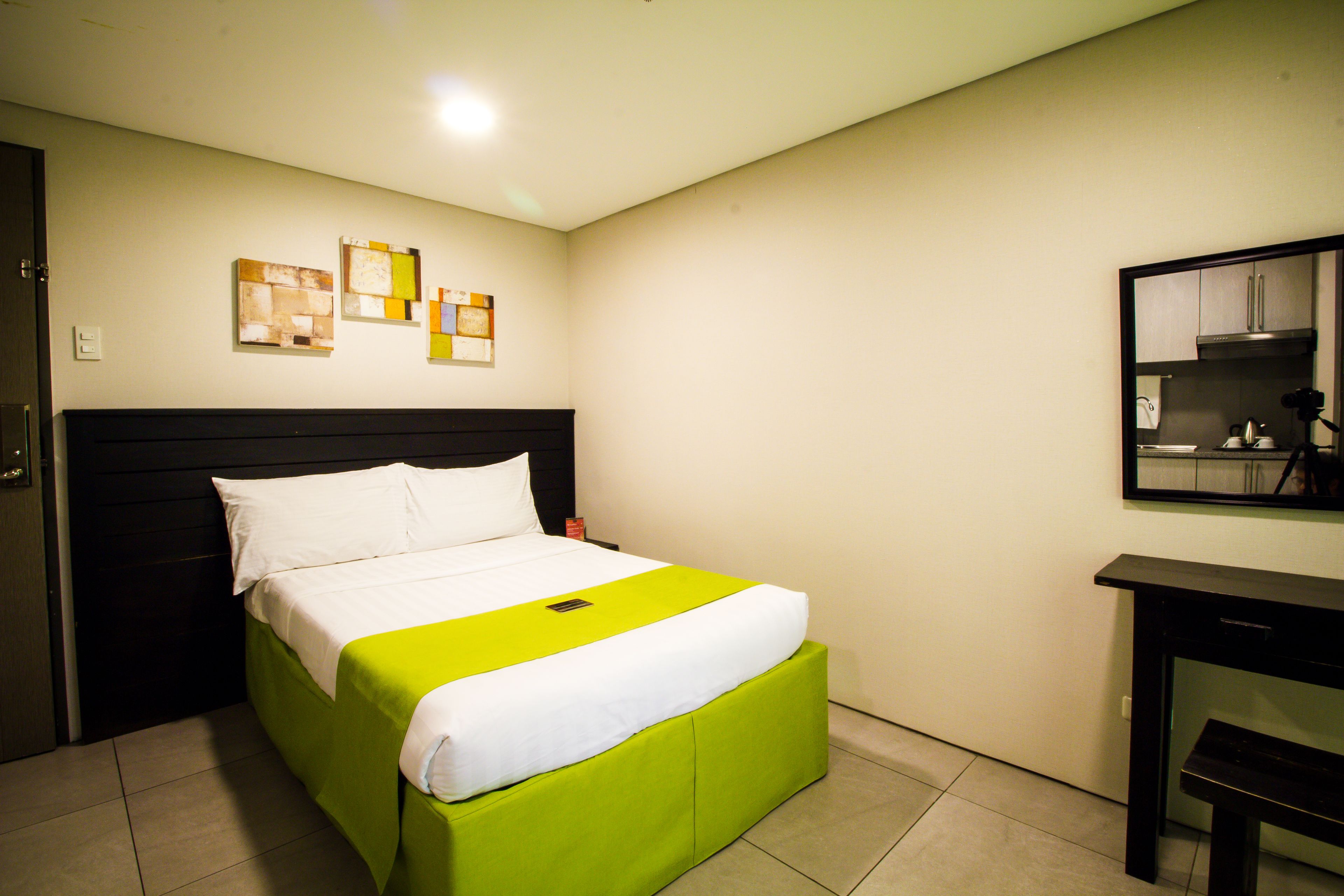 Una camera d'albergo con un letto, una scrivania e uno specchio.