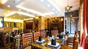 A restaurant with wooden tables and chairs, brick walls, and hanging pendant lights. - Jade Hotel & Suites (Makati)