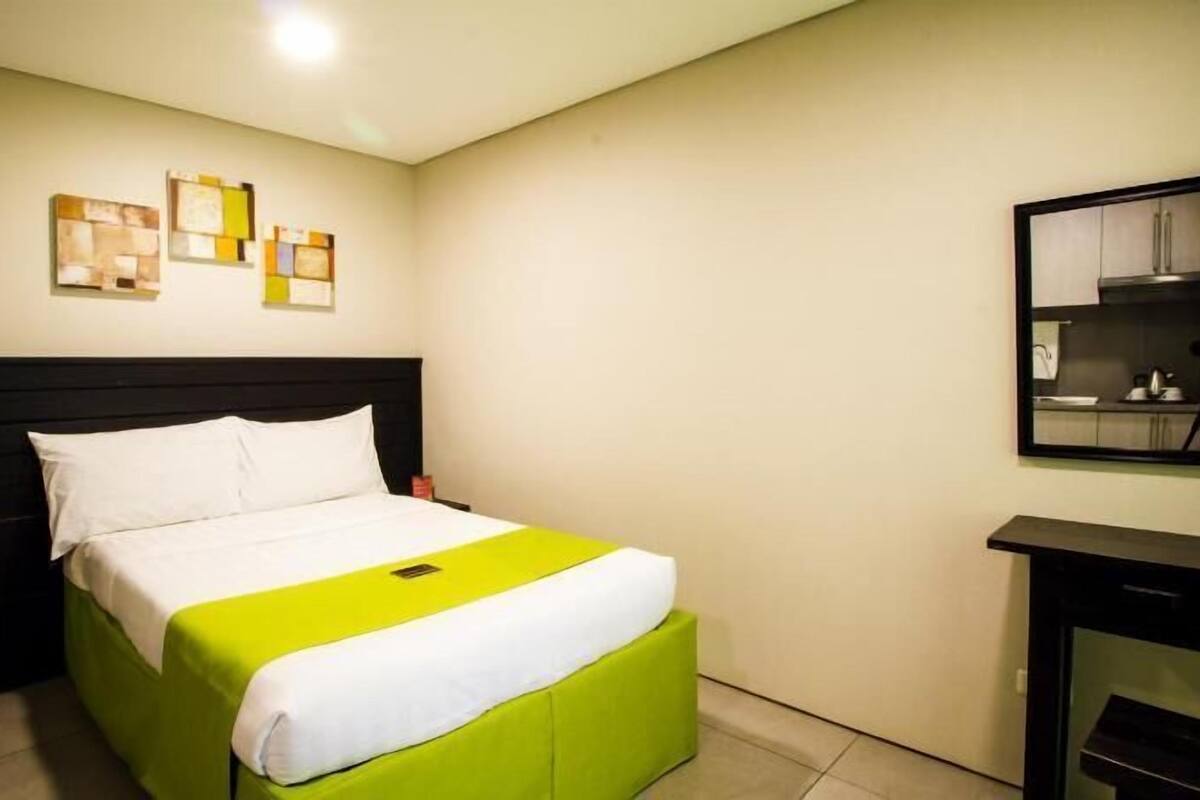 A hotel room with a bed, a nightstand, a mirror, and a wall with abstract art.