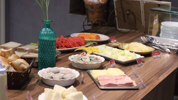 A buffet table with various food items including fruits, cheeses, and meats.