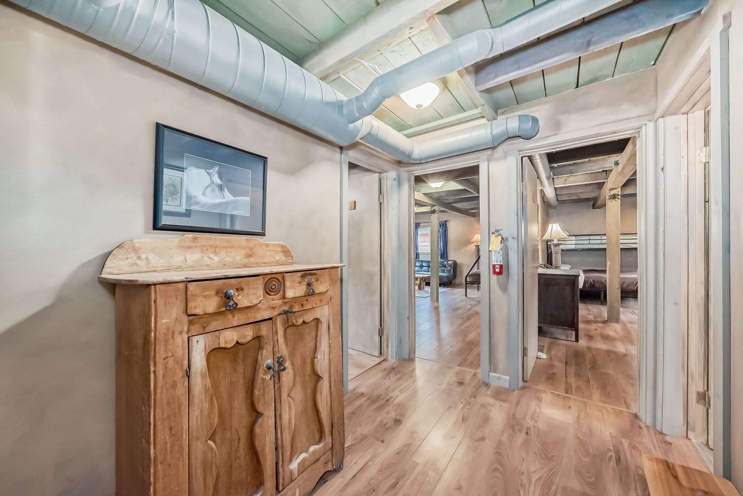A hallway with wooden flooring, a wooden cabinet, and a framed picture on the wall.