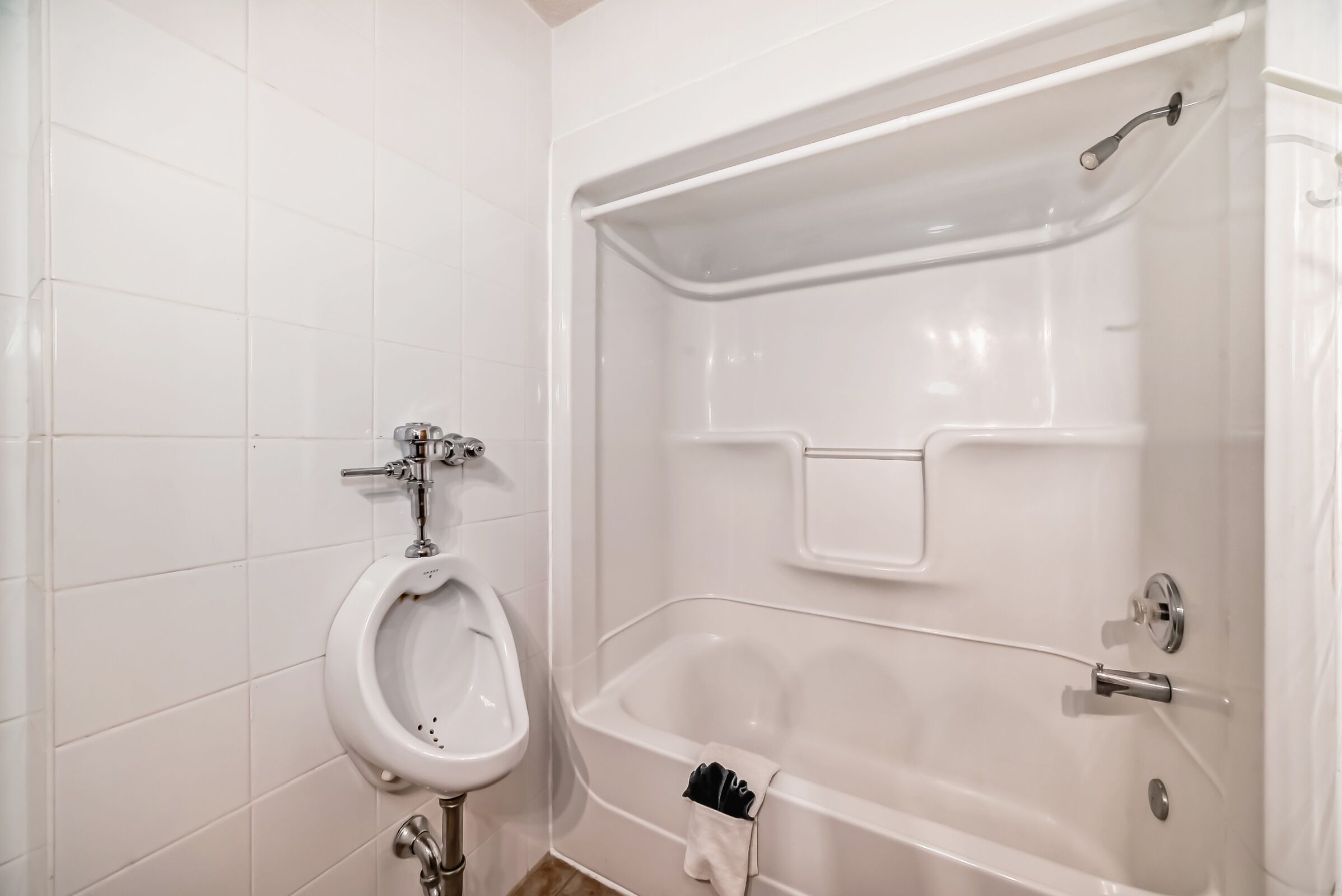 Une salle de bain équipée d’un urinoir, d’une baignoire et d’une douche.