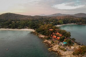Zona costera con playa, costa rocosa y un edificio de techo rojo.