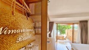 Ein Zimmer mit einem Bett, Holzboden, einem großen gewebten Korb mit Text und Blick auf einen Außenbereich.