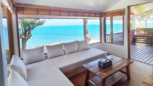 Ein modernes Wohnzimmer mit einer großen Couch, einem Couchtisch und Blick auf den Ozean.