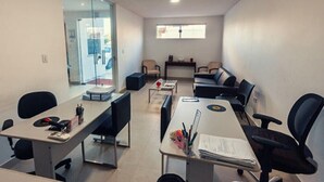 Un salón de conferencias con paredes de vidrio, un ventanal grande y varias mesas con sillas.