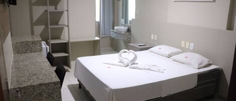 Habitación de hotel con cama, baño, escalera y un cuadro en la pared.