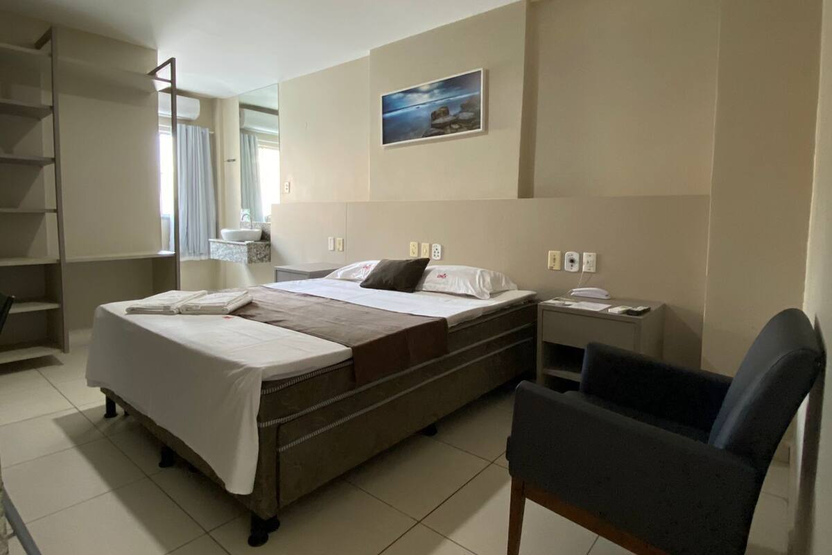 Habitación de hotel con dos camas, un escritorio, una silla, un baño y un cuadro en la pared.