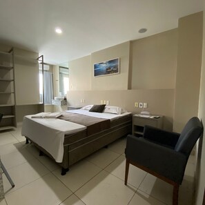 A hotel room with two beds, a desk, a chair, a bathroom, and a painting on the wall. - Onix Hotel Aeroporto (Lauro de Freitas)