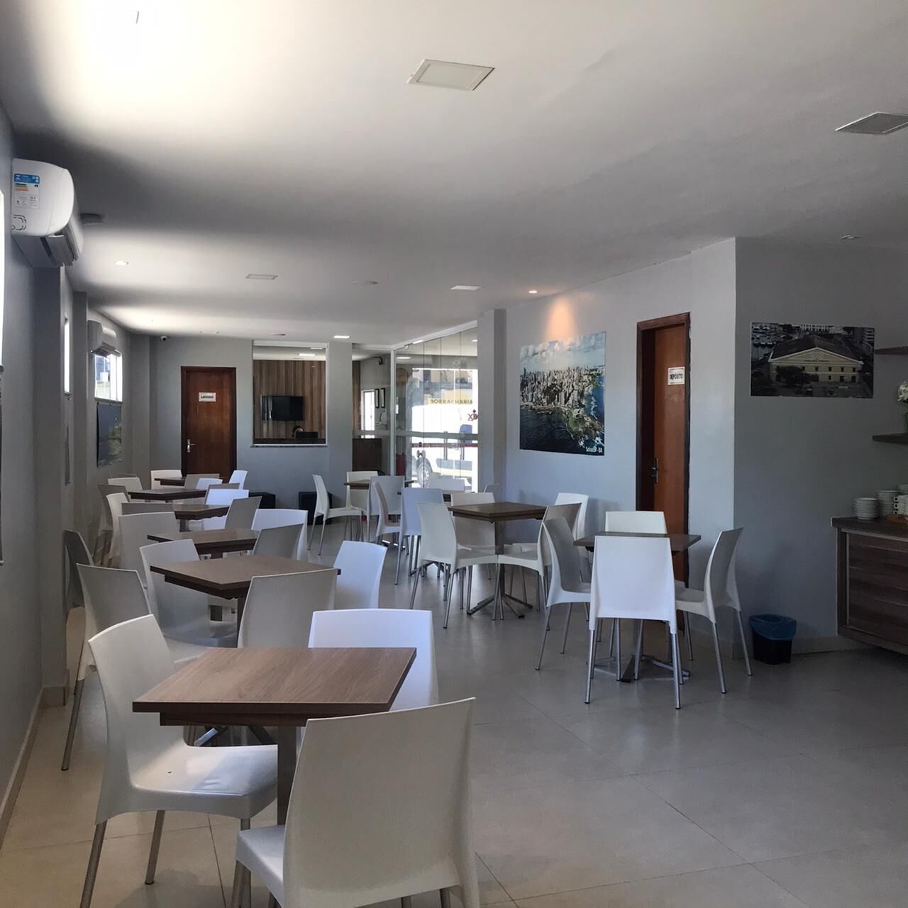 A spacious dining area with multiple tables and chairs, a television mounted on the wall, and a door labeled "Lobby".