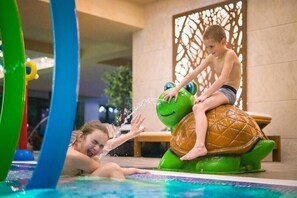 Un enfant est assis sur une structure aquatique en forme de tortue dans un espace piscine.
