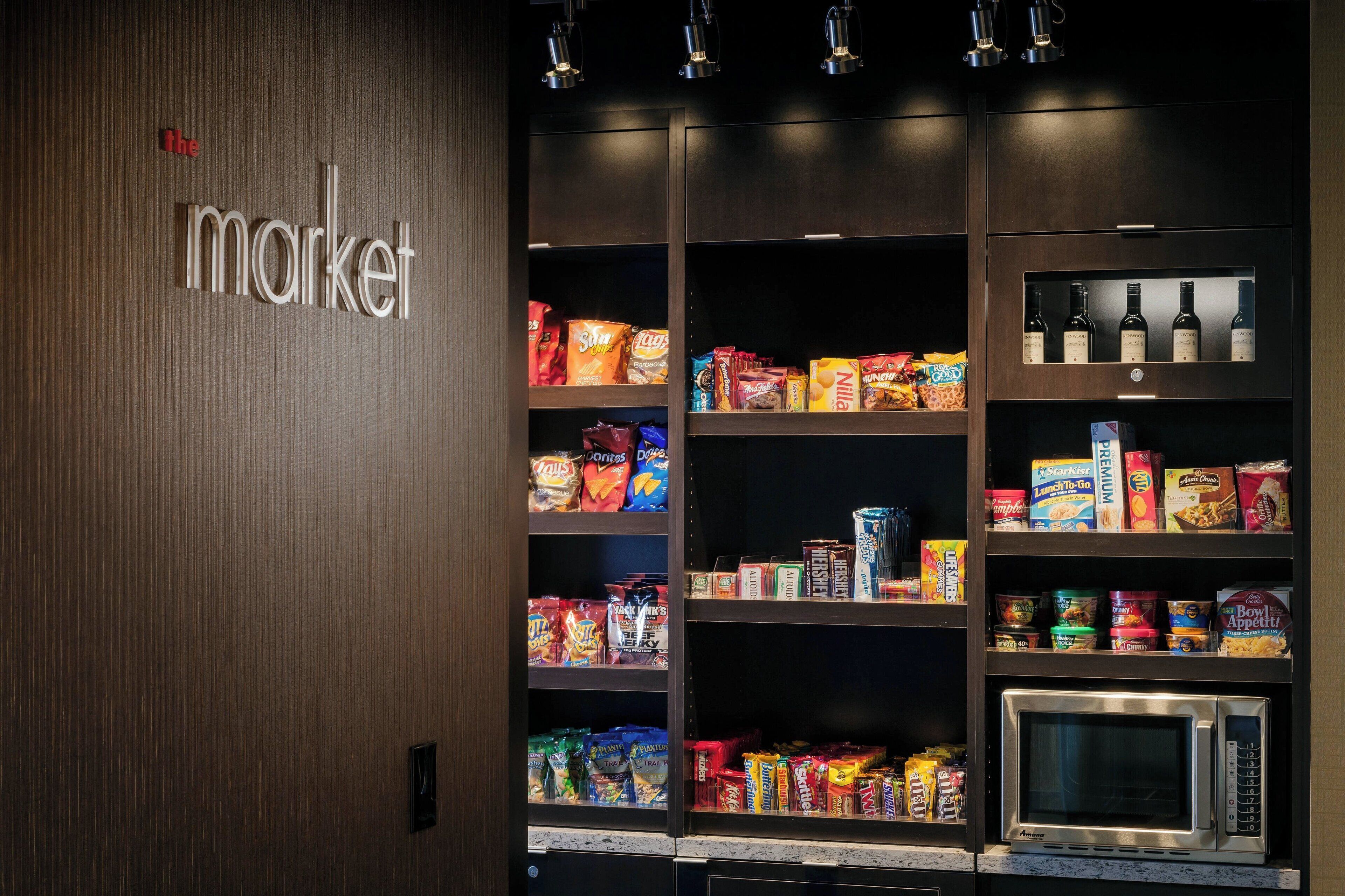 Ein Verkaufsautomatenbereich mit Snacks und Getränken, einer Mikrowelle und einem Schild mit der Aufschrift 'the market'.