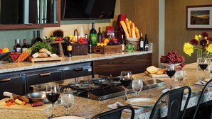 A modern kitchen with a built-in stove, a dining area with chairs, and a variety of food and drink items on the counter. - Courtyard by Marriott Walla Walla (Walla Walla)