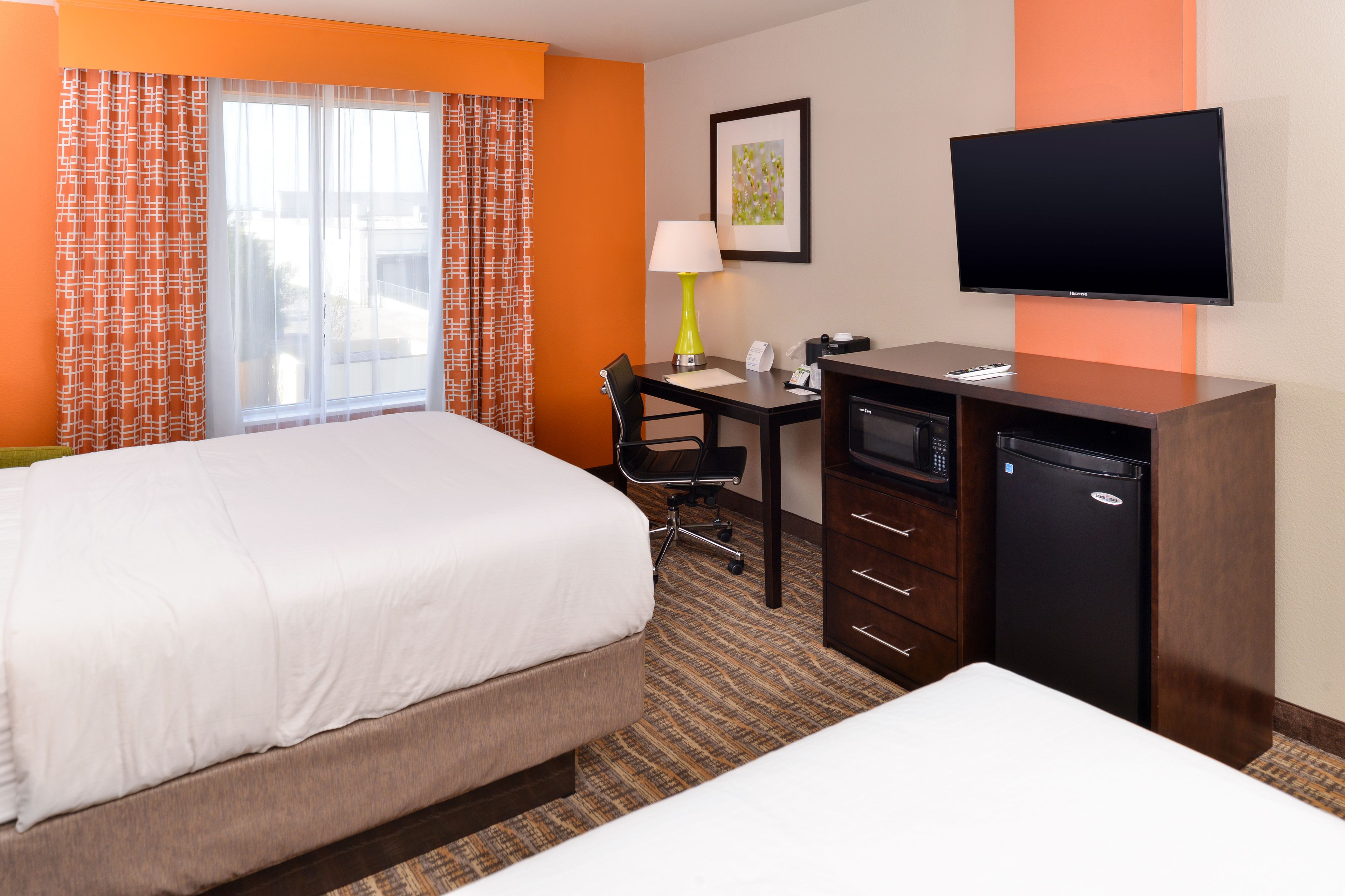 Una habitación de hotel con cama, escritorio, televisión y minibar.