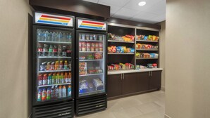 A vending area with two refrigerated beverage dispensers and shelves stocked with snacks and beverages.