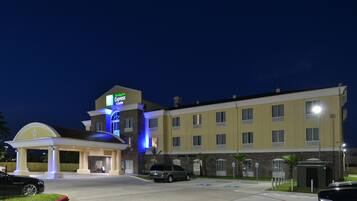 A hotel with a gas station, multiple floors, and a parking lot.