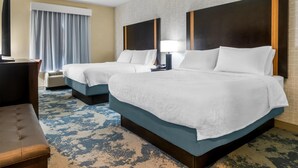A hotel room with two beds, a desk, a chair, a lamp, and a large window with curtains. - Hampton Inn Marion (Marion)
