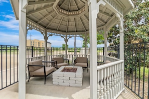 A gazebo with a hexagonal roof, outdoor seating with cushioned chairs, and a central fire pit. - Hampton Inn Marion (Marion)