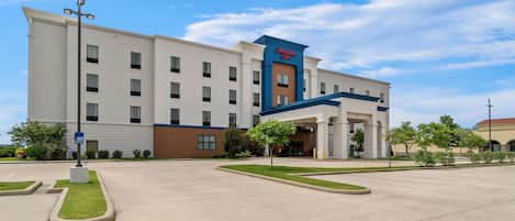 Un hotel grande con una entrada destacada, varios pisos y un cielo despejado.