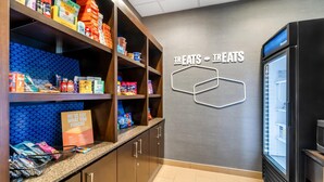 A kitchenette with shelves stocked with snacks and a refrigerator. - Hampton Inn Marion (Marion)