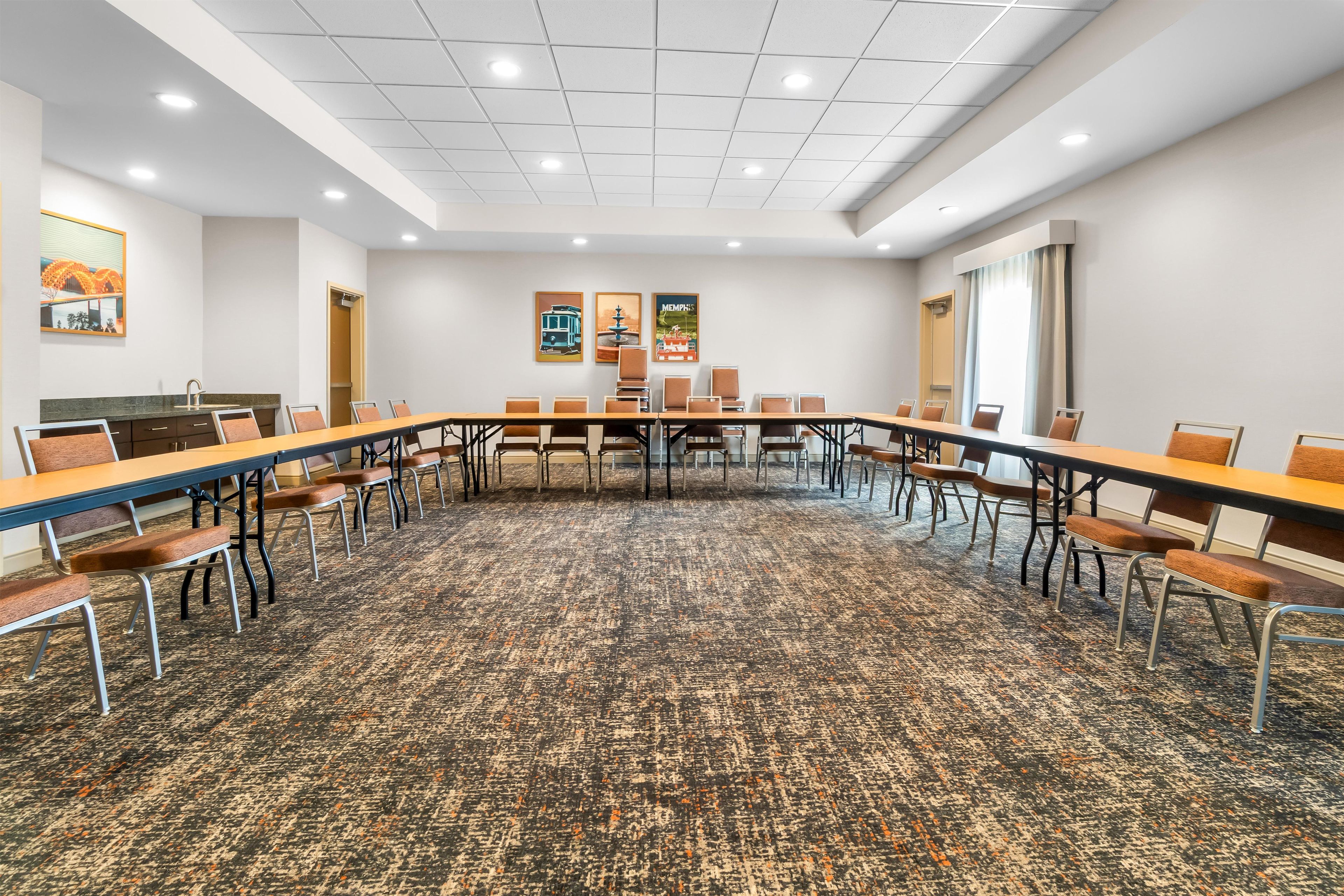 A conference room with a long table, chairs, and a carpeted floor.