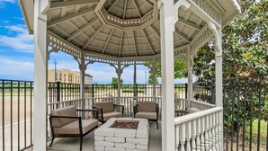 A gazebo with a hexagonal roof, outdoor seating with cushioned chairs, and a central fire pit. - Hampton Inn Marion (Marion)