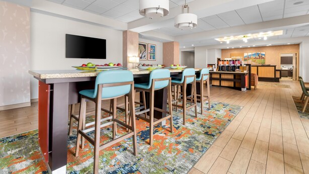 A modern hotel lobby with a bar area, seating, a flat-screen TV, and a reception desk. - Hampton Inn Marion (Marion)