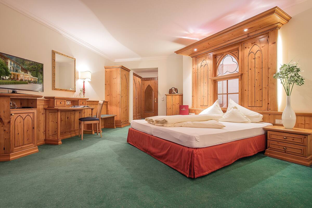 Un dormitorio con una cama grande, muebles de madera, un escritorio y una silla.