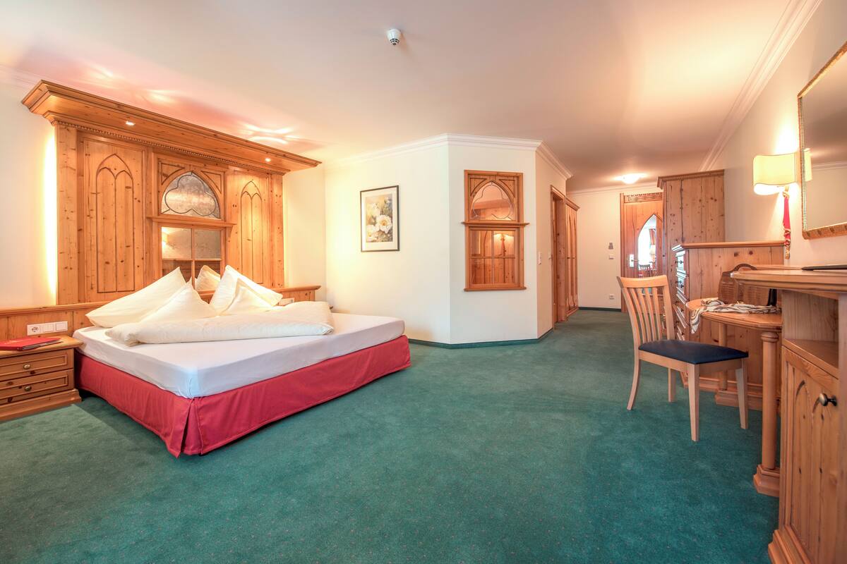 Un dormitorio con una cama grande, un armario de madera y un escritorio con silla.