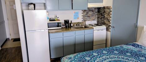 Cocina compacta equipada con refrigerador, microondas, cafetera y estufa.