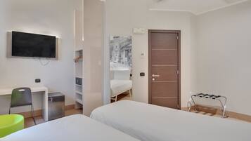 Una habitación de hotel moderna con cama, escritorio, silla, armario y televisor.