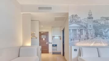 Une chambre d’hôtel avec deux lits, un couloir et une vue sur une rue de la ville, avec un beffroi en arrière-plan.