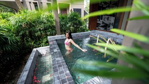 Una donna in piscina, con bordi piastrellati e una scaletta in legno.