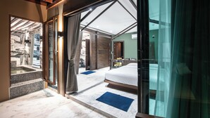 Una moderna camera d'albergo con un letto grande, una porta vetrata che dà su un balcone e vista sulla zona della piscina.