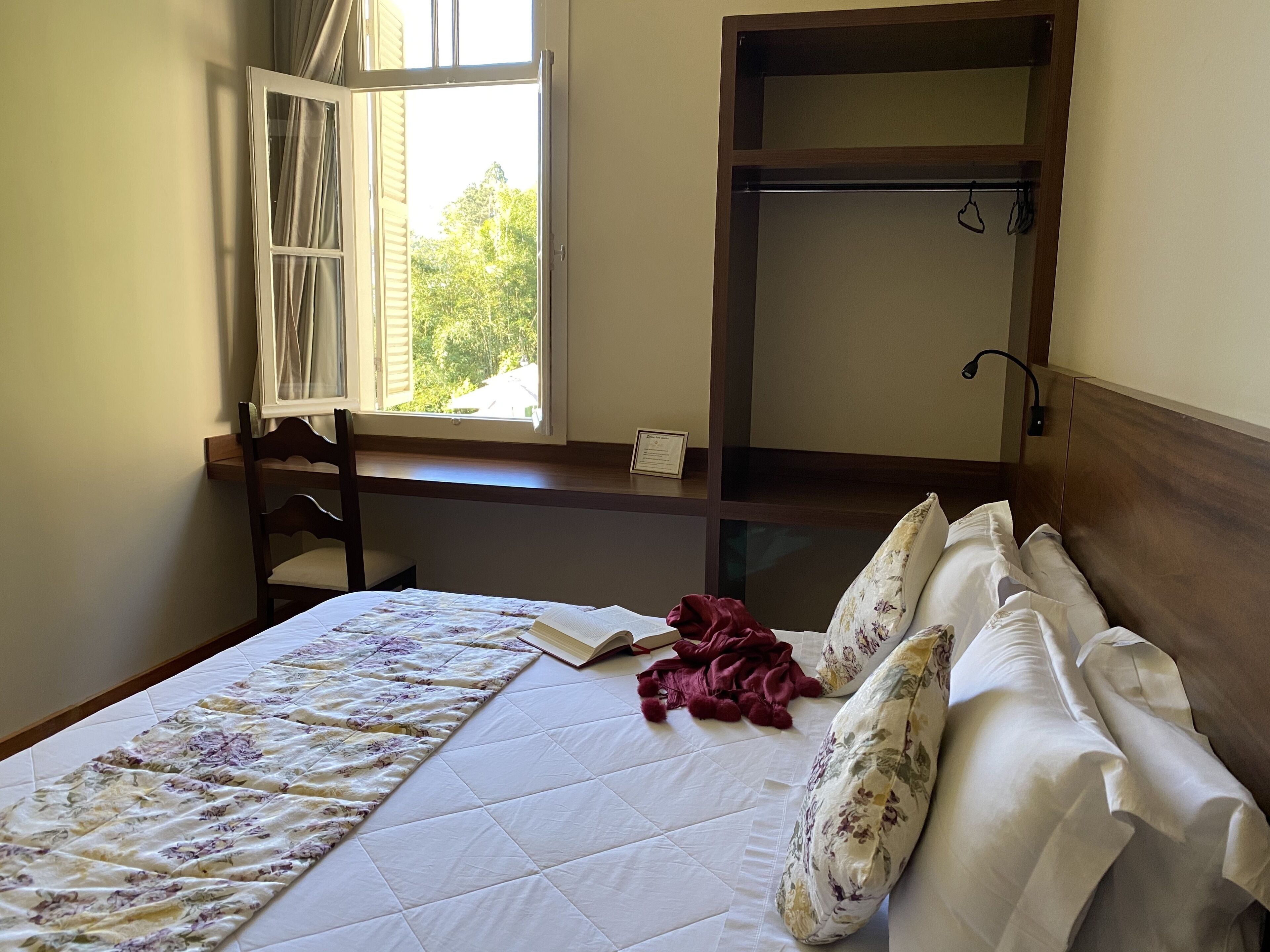 A bedroom with a bed, a window, a desk, and a wardrobe.