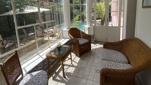 A sunlit room with large windows, wicker furniture, and a tiled floor. - Pousada Princesa Isabel - Visconde (Petrópolis)